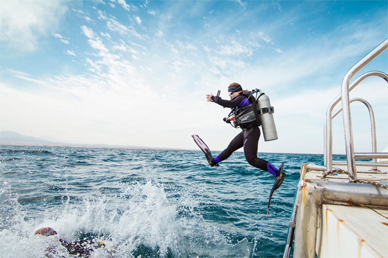 Diver jumping into the water from a dive boat operated by Breakers Diving Lodge in Soma Bay