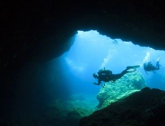 Divers by a cave entrance in Malta