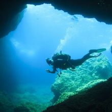 Divers by a cave entrance in Malta