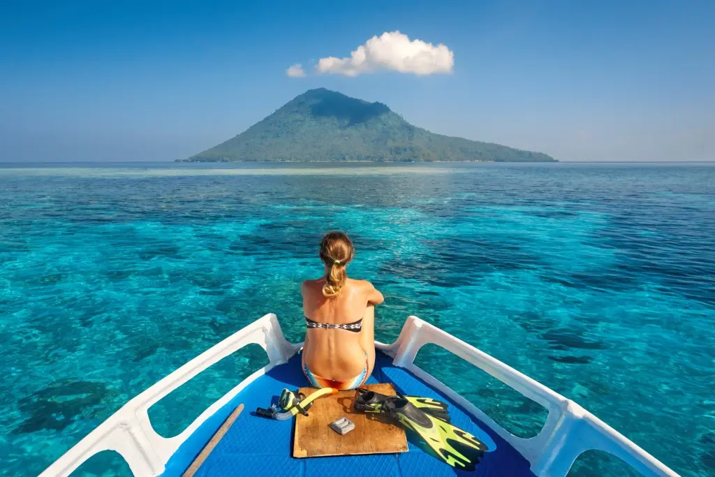 Girl on a boat facing Manado Tua in Indonesia
