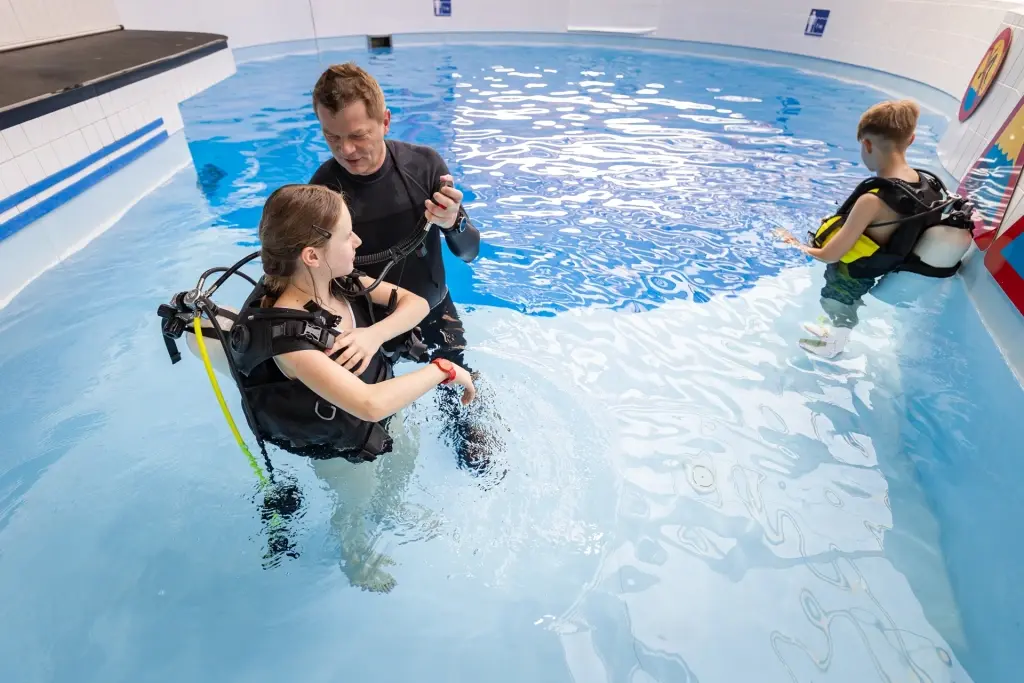 Student being taught by a dive instructor how to dive in a swimming pool