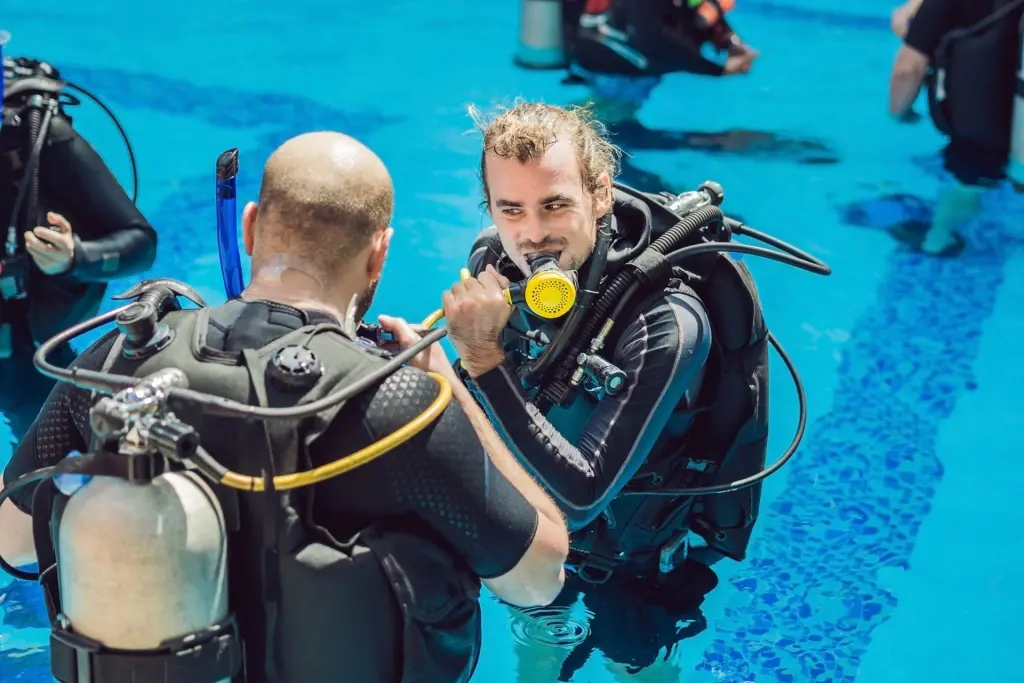 Student being taught by a dive instructor how to dive in a swimming pool