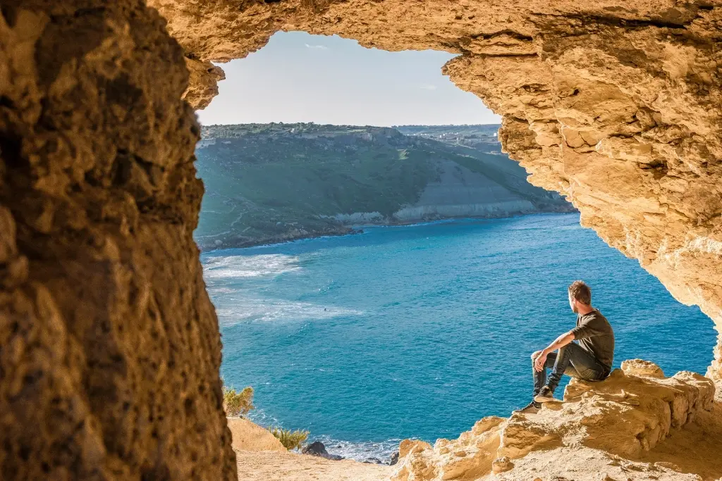 Person inside Mixta Cave which looks over Ramla Bay in Gozo