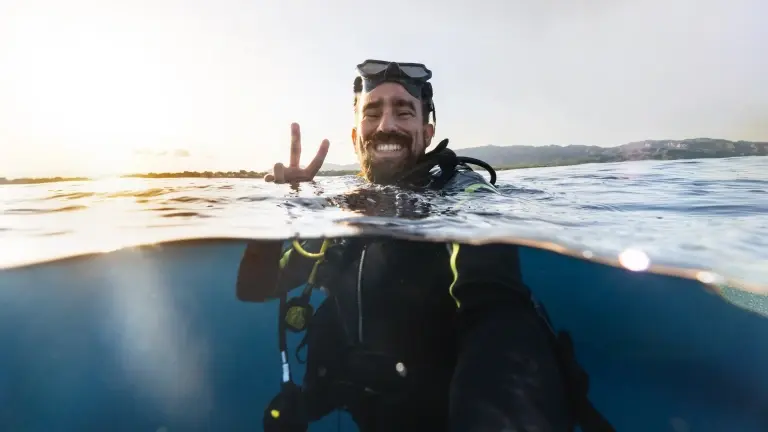 Diver doing the peace sign at the surface of the water