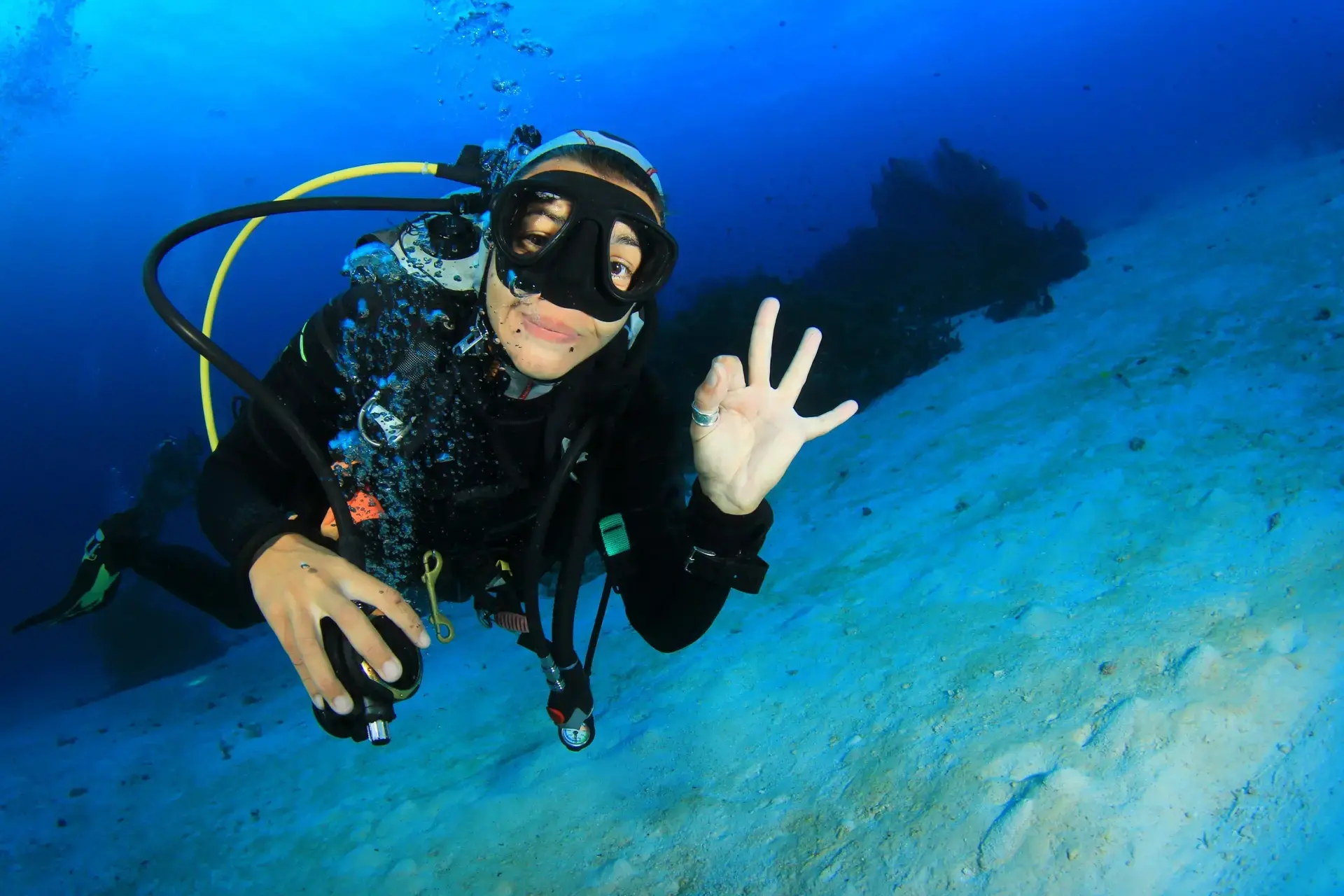 Woman diver holding up an ok sign underwater, Thailand