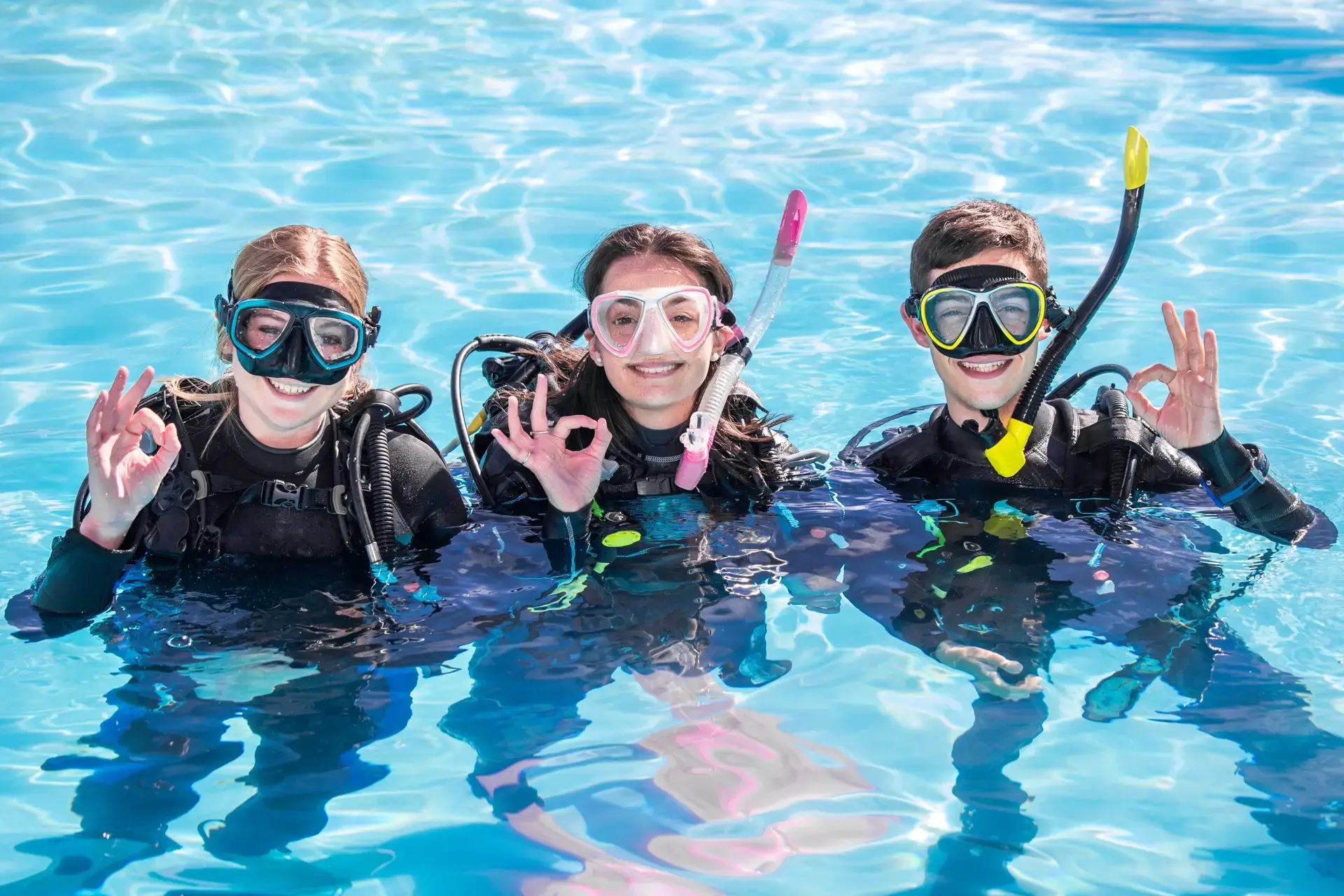 Three divers learning to dive with the 'okay' sign