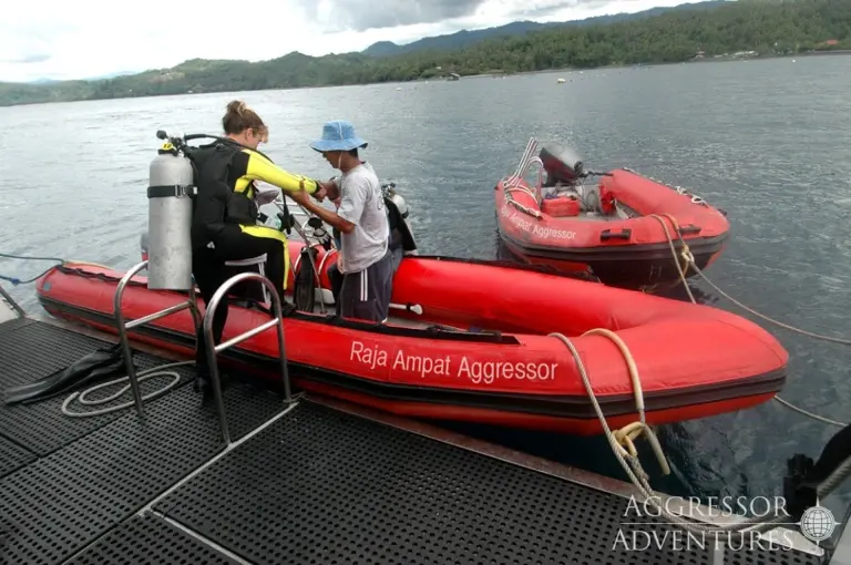 Diver embarking on a Raja Ampat Aggressor zodiac, in Indonesia.