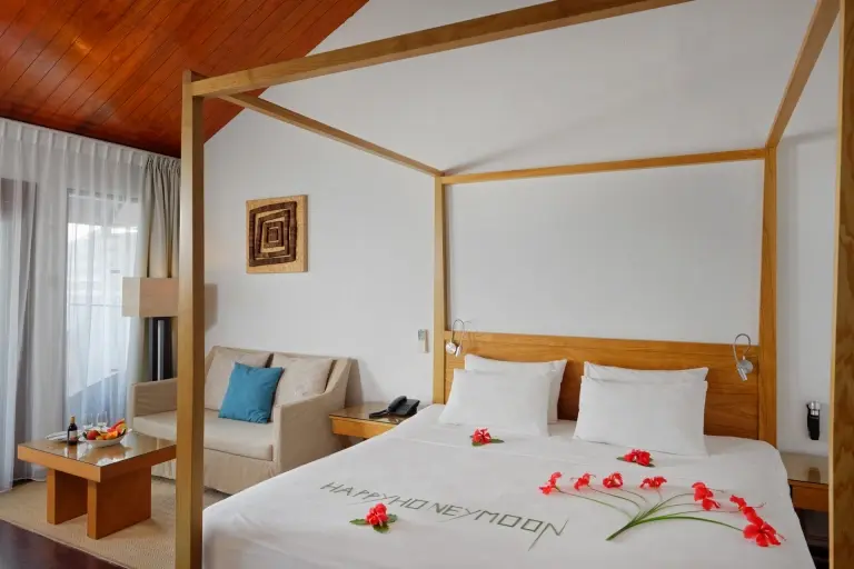 Overwater villa with 'Happy Honeymoon' spelt out on the bed, at Embudu Village accommodation in the Maldives